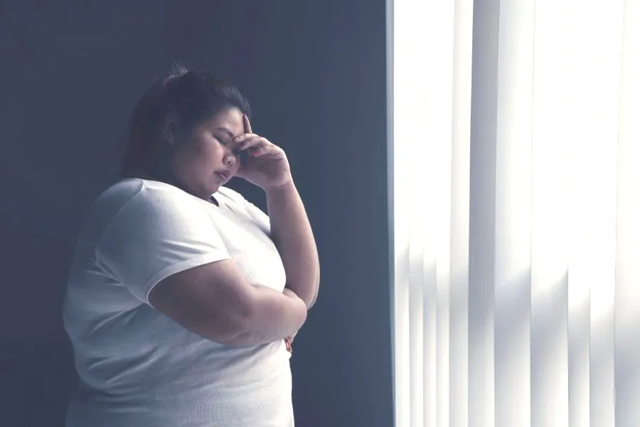 concerned obese woman standing by window
